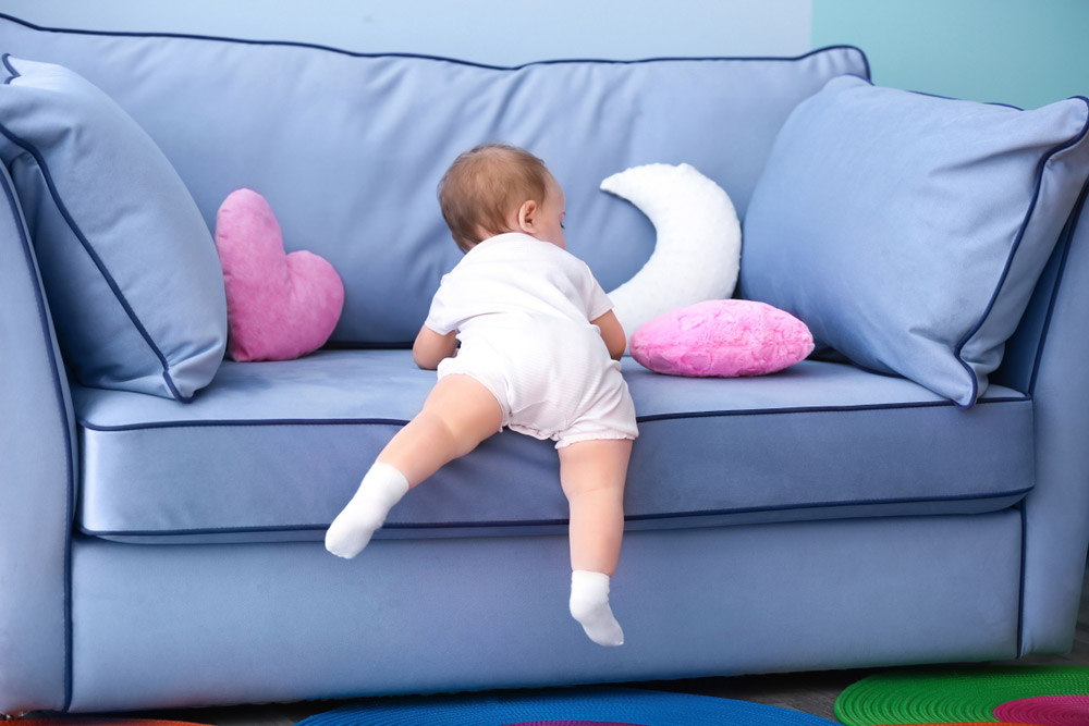 A 10 hónapos baba felmászik a kanapéra.